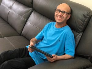A smiling tenant sitting on a sofa holding a tablet